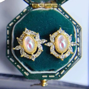 Vintage gold earrings with oval moonstone centers and petal diamond halos in velvet box