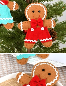 Detail of gingerbread man Christmas ornament with red overalls on a festive tree branch