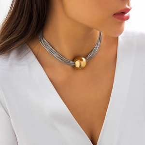 Detail of layered silver chain necklace with a large gold bead pendant on a model