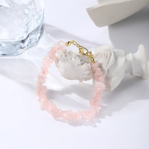 Detail of a natural rose quartz chip bracelet with a gold lobster clasp and extension