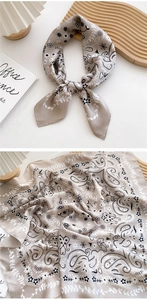 Detail of taupe silk scarf with paisley print showing soft texture and folded pattern
