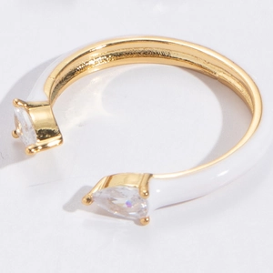 Macro shot of gold-plated open ring with white enamel and pear-shaped zircon details