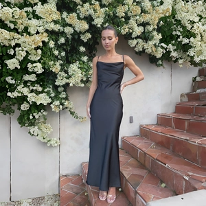 Detail of elegant black satin dress featuring a cowl neckline and slim spaghetti straps