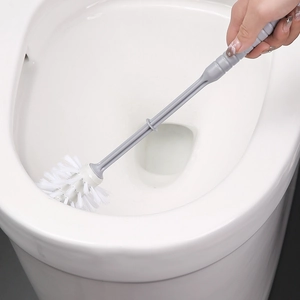 Long-handled gray toilet brush with white bristles being used inside a clean white toilet