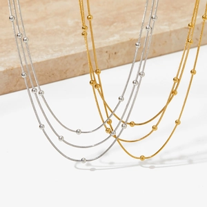 Vue détaillée de colliers multicouches en acier inoxydable perlé or et argent sur marbre