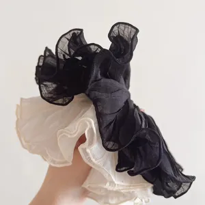 Detail of layered pleated organza scrunchies in black and beige with wavy edges