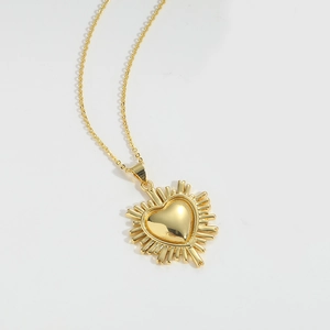 Macro detail of a golden radiant heart pendant on a delicate link chain for women