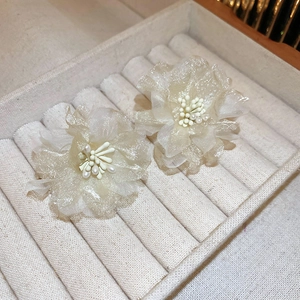 Close-up of mesh flower earrings with pearl bead center in cream velvet jewelry box