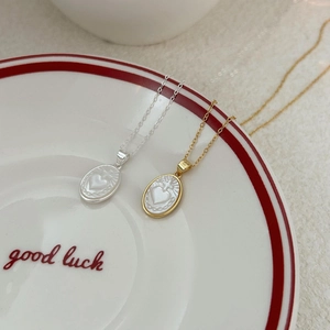 Elegant 925 silver mother of pearl heart and cross necklaces on a ceramic plate