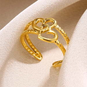 Detail of gold-plated open ring featuring a double heart motif and twisted rope band texture