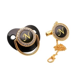 Detail of luxury black pacifier set with gold letter N and rhinestone clip