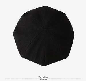Top down view of a black knitted beret hat showing fine vertical texture and top stem detail