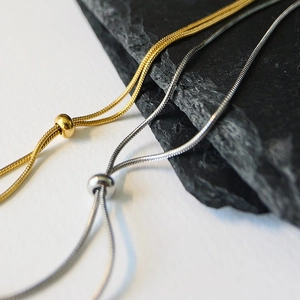 Detail of adjustable gold and silver snake bone necklaces with sliding bead clasps