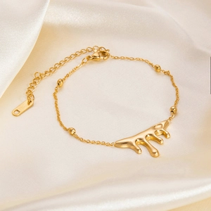 Lava droplet gold bracelet with heart and star accents on elegant silk fabric