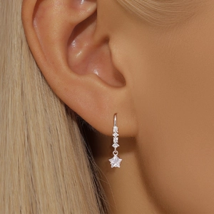 Detail of star-shaped silver drop earring with sparkling zircon stones on a model