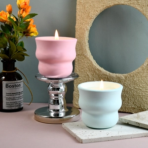 Portacandele ondulati in ceramica rosa e verde acqua su un supporto in metallo argento