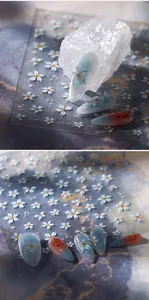 Dettaglio macro di adesivi per unghie M-575 fiori blu e rilievi dorati su marmo