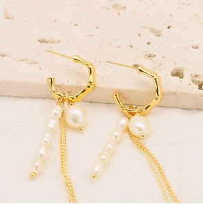 Detail of gold bamboo style earrings with hanging natural pearls and delicate tassels