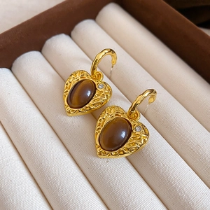 Detailed view of heart-shaped gold earrings with brown tiger eye stone and crystals