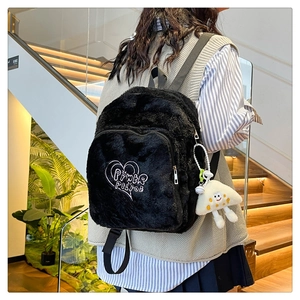 Detail of black faux fur backpack featuring white heart embroidery and cartoon charm
