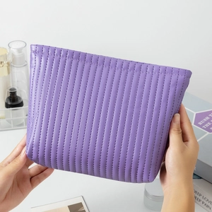 Close-up of hand-held purple quilted leather cosmetic bag with a large capacity