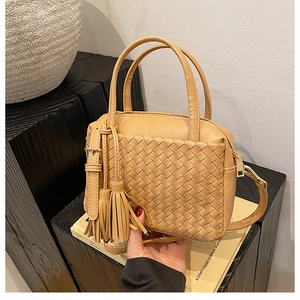 Close-up of camel hand-woven tote bag with elegant tassel detail and PU leather texture