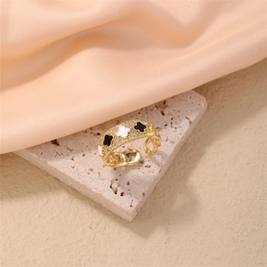 Detail of gold chain ring featuring black and white clover charms with crystal inlays