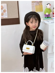 Close-up of a white quilted mini crossbody bag with gold chain strap on a young girl