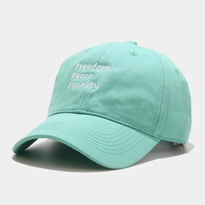Detail of white Freedom Peace Equality embroidery on a mint green cotton baseball cap