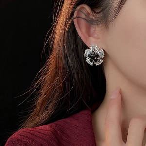 Detail of flower stud earrings with black center stone and zircon petals on a model