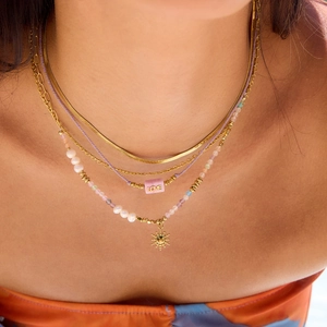 Layered gold necklace set with freshwater pearls, colorful beads and a sun pendant charm