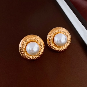 Detail von Vintage-Ohrsteckern aus gold gehämmertem Metall mit weißen Perlen