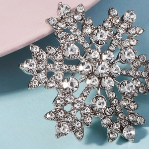 Close-up of silver snowflake brooch with shimmering crystals and elegant rhinestone design