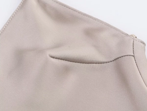 Dettaglio del tessuto satinato beige chiaro con pizzo delicato e cuciture di qualità