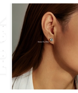 Primo piano di orecchini azzurro chiaro da 6mm con montatura in argento sull'orecchio