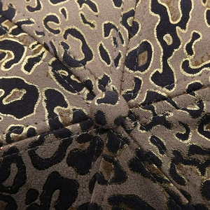 Macro view of gold leopard print baseball cap featuring suede fabric and premium stitching