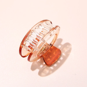 Close-up of translucent orange-brown acetate hair claw clip with cutout texture on pink