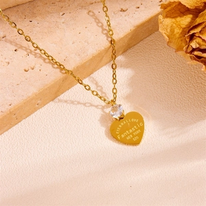 Detail of golden heart pendant necklace with clear gemstone and eternal love engraving
