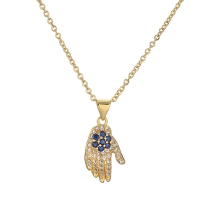 Detailed macro view of gold-plated Hamsa pendant with blue and white zircon stones