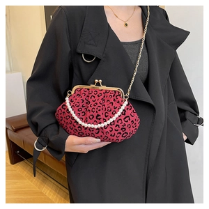 Detail of red leopard print shell bag with pearl handle and golden chain on black coat