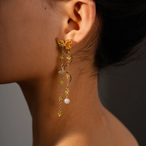 Detailed view of elegant gold tassel earrings with yellow butterfly crystal and white pearl