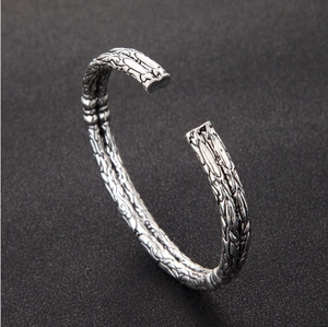 Close-up of vintage silver open cuff bracelet with detailed dragon scale metal texture