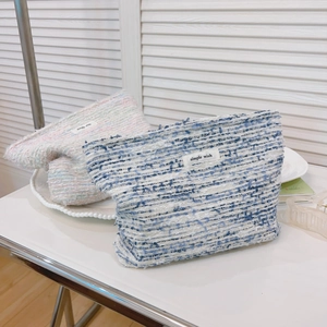 Tweed weave cosmetic bags in blue-white and pink-green colors on a minimalist desk