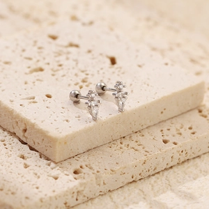 Macro detail of S925 silver stud with pear-shaped cubic zirconia on beige stone
