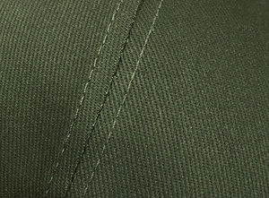 Gros plan sur un tissu sergé vert foncé avec double couture renforcée pour casquettes