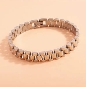 Detailed close-up of golden stainless steel watchband style bracelet with fold-over clasp