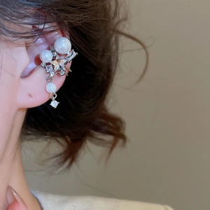 Close-up of elegant star zircon and pearl ear cuff worn on a woman's earlobe