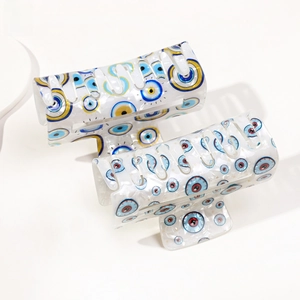 Detailed view of two PVC hair claw clips with evil eye print and pearlescent finish