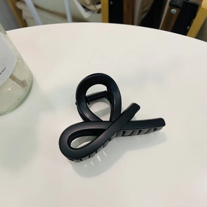 Detailed macro view of a matte black shark hair claw clip with a cross knot design