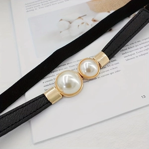 Close-up of black elastic belt with gold metal buckle and two large decorative pearls